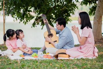 Young Asian family having a picnic in the park on the weekend
