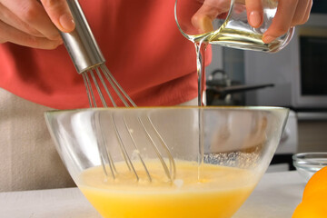 Pastry chef woman hands cooking pouring oil into batter in glass bowl on kitchen. Professional baker preparing ingredients for homemade pie. Culinary skills, cuisine, dish meal. Domestic recipe.