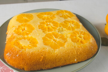 Delicious just baked tangerine biscuit cake rotating on a plate on kitchen. Professional pastry chef preparing citrus orange dessert, cooking homemade sponge cake pie. Culinary, cuisine, recipe.