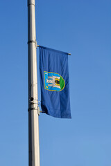 A blue banner featuring the coat of arms of the city of Zagreb hangs from a pole under a clear blue sky