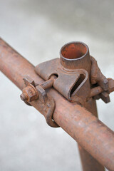A rusty metal clamp tightly fastens two cylindrical pipes together, exhibiting signs of wear and age