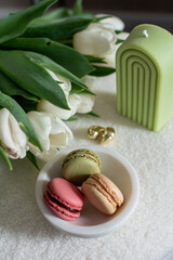 Cup with cappuccino and macarons, spring flowers tulips, morning concept, soy candle, woman's day, bedroom design