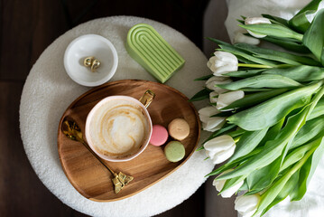 Cup with cappuccino and macarons, spring flowers tulips, morning concept, soy candle, woman's day, bedroom design