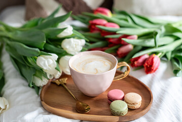 Cup with cappuccino and macarons, spring flowers tulips, morning concept, soy candle, woman's day, bedroom design