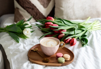 Cup with cappuccino and macarons, spring flowers tulips, morning concept, soy candle, woman's day, bedroom design
