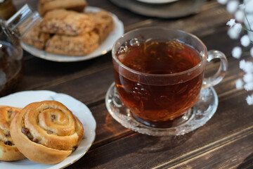 Transparent cup of tea and fresh pastries on kitchen table. 