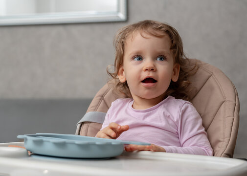 A surprised toddler showing excitement and curiosity during mealtime at home.