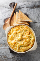 Baked Cheesy Mashed Potatoes with parmesan and cheddar closeup on the baking dish on the table. Vertical top view from above