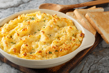 Close-up of mashed potato casserole with cheese, cream and butter in a baking dish on the table. Horizontal