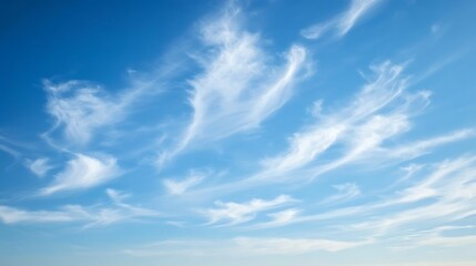 Obraz premium Wispy white clouds drift across a blue sky
