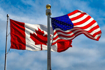 Canada and USA flags flying in strong wind