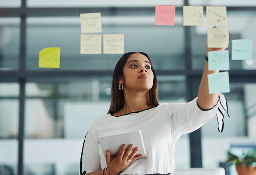 Glass wall, sticky note and businesswoman with tablet in office with information for research on media project. Board, creative and public relations officer working on press report in workplace.