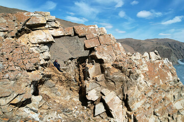 Fototapeta premium The girl in the stone arch in the rock. Hiking, the concept of freedom, outdoor activities, extreme sports.