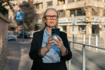 A confident business woman is seen in an urban environment using her smartphone effectively