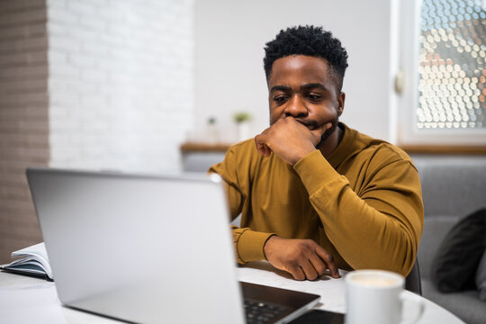 Worried African American businessman using laptop while working  from his home.