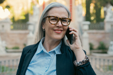 A Confident Mature Woman Engaging in a Phone Conversation While in an Urban Environment