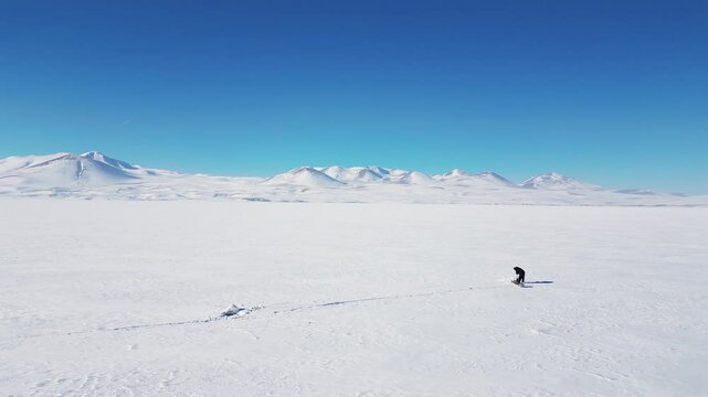 Aerial panoramic view with rotation around ice fisher on frozen Paravani lake in Georgia
