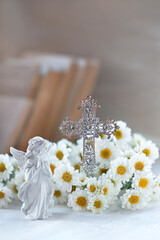 Beautiful angel figurine with christianity openwork cross and flowers on table close up. symbol of Christianity religion, faith in God, prayer, memory. christian home altar