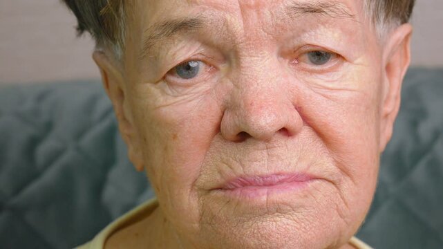 The sad look of very old woman. Flabby and wrinkled skin on the face an elderly woman. Loneliness and depression are reflected in her eyes, she looks at the camera. Concept of old age and retirement