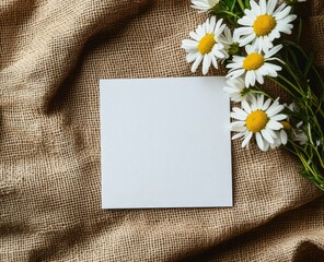 Photo of a white blank card and a bouquet of daisies on a brown jute background, a mockup template for postcard design. 