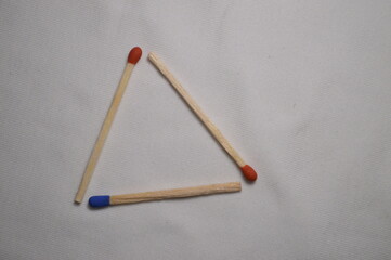 Three matches create a simple triangle shape against a clean white backdrop.