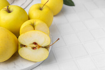 Fresh ripe yellow apples on white tiled table, closeup. Space for text