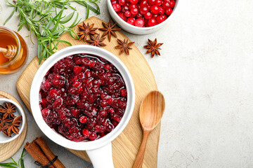 Tasty cranberry sauce in gravy boat, berries, honey and spices on light table, flat lay. Space for text