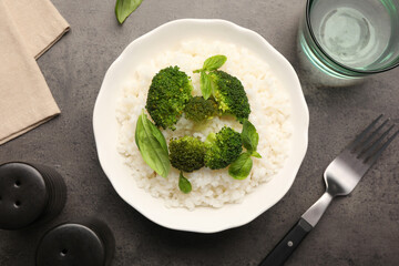 Tasty rice with broccoli served on grey table, flat lay