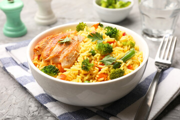 Tasty rice with vegetables and chicken on grey table, closeup
