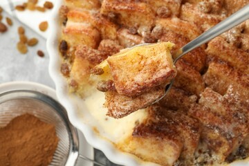 Eating delicious bread pudding with cinnamon at table, closeup