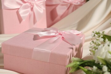 Beautiful wedding gifts, silk fabric and flowers on table, closeup