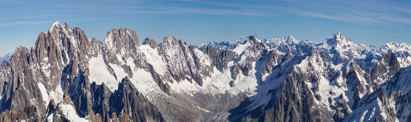 Generated ImageBreathtaking panoramic view of the snow-covered Alps from Aiguille du Midi, Chamonix. Majestic peaks, deep valleys, and vast glaciers under a clear blue sky create an unforgettable alpi