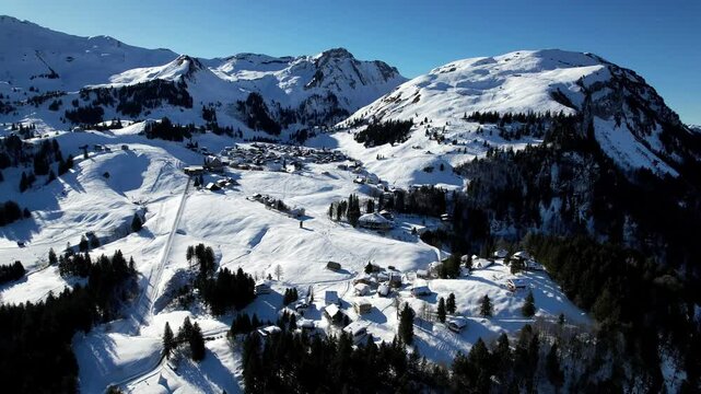 A beautiful aerial view of the Stoos ski resort in the Swiss Alps. Snow-covered chalets and ski slopes create a perfect winter getaway for skiers and travelers