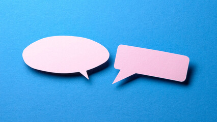 Pink blank cut out paper speech bubbles with copy space for text on blue background, flat lay top view discussion conversation concept