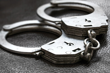 Closeup of handcuffs on a dark background, emphasizing detail and creating tension