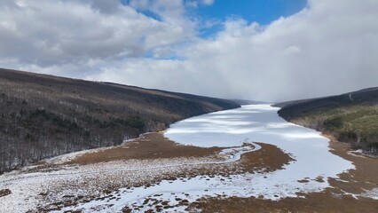 Ancient Glacier finger lake Hemlock Lake, NY during Winter in freezing conditions ideal for ice fisherman landscape with cloud shadows on snow covered lake