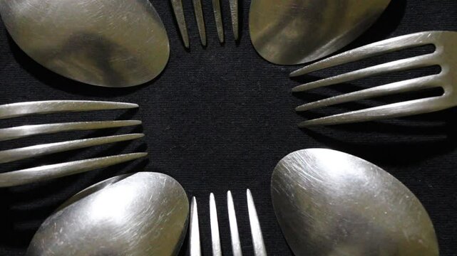 Cucharas grandes y peque&ntilde;as en c&iacute;rculo, son herramientas culinarias para comidas variadas, forman un dise&ntilde;o de brillos y texturas abstractos con fondo negro