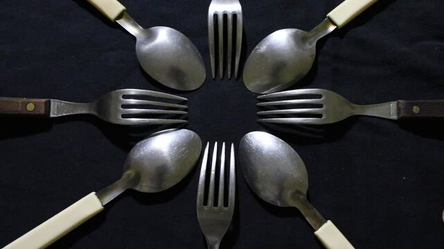 Cucharas grandes y peque&ntilde;as en c&iacute;rculo, son herramientas culinarias para comidas variadas, forman un dise&ntilde;o de brillos y texturas abstractos con fondo negro