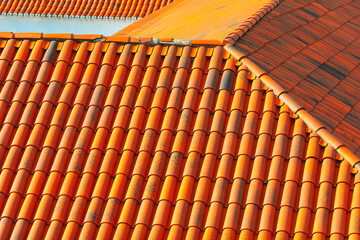 Textured surface of a traditional terracotta tile roof. Rooftop covered with orange terracotta tiles highlighting the durability and weathering of traditional roofing materials