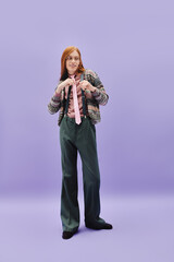 Stylish young queer man in modern outfit poses confidently against a vibrant background