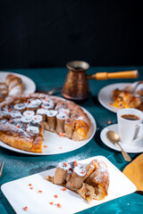 A piece of banana cake or pie and a cup of Turkish coffee on a white plate on a turquoise background. French dessert on the table. Vertical photo.