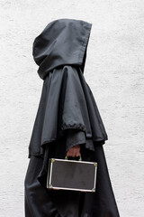 A mysterious wanderer in a dark cloak carrying a traveling suitcase.