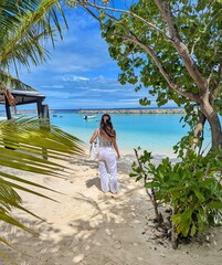 A stunning white sand beach in Maafushi, Maldives, featuring clear blue waters and palm trees.