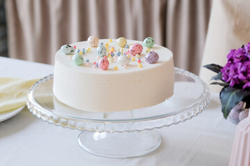 Easter cake in pastel colors decorated with sweet eggs in the kitchen