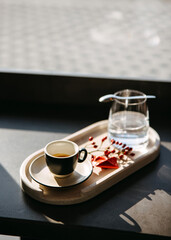 Minimalist coffee moment with an espresso on a wooden tray, in warm morning sunlight.