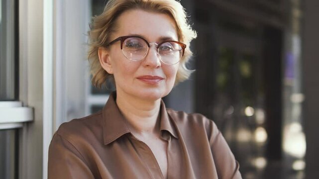 Close-up portrait of serious adult mature woman in eyeglasses looking with self-confident expression, looking for solution for hard decision, used to relying only on herself, bottom-view
