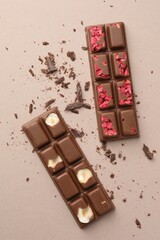 Tasty chocolate bars and crumbs on beige background, flat lay