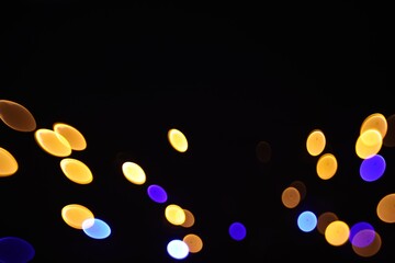 Blurred view of colorful lights on black background, bokeh effect