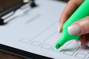 Woman checking box of paper form at wooden table, closeup