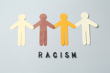 Word Racism and human paper figures of different colors on light grey background, top view